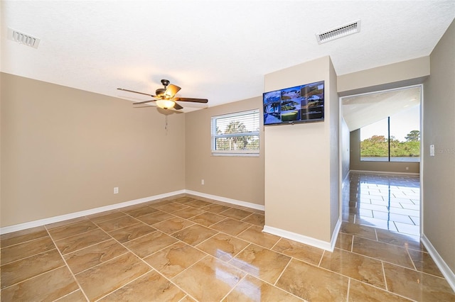 unfurnished room featuring visible vents, baseboards, a textured ceiling, and ceiling fan