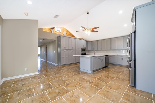 kitchen featuring tasteful backsplash, visible vents, lofted ceiling, gray cabinets, and a sink