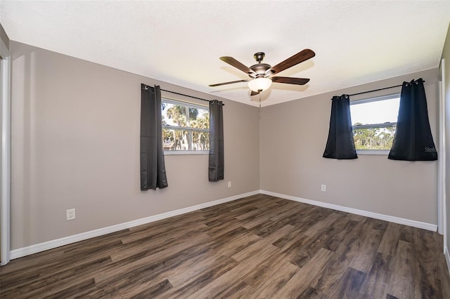 empty room featuring dark wood-style floors, baseboards, and a wealth of natural light