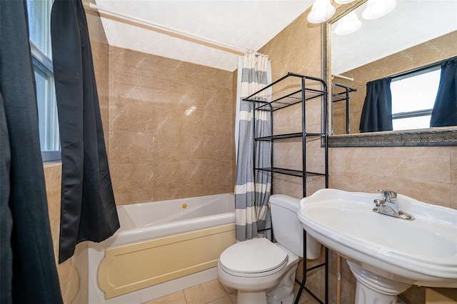 full bath featuring tile patterned flooring, toilet, shower / bath combination with curtain, tile walls, and a sink