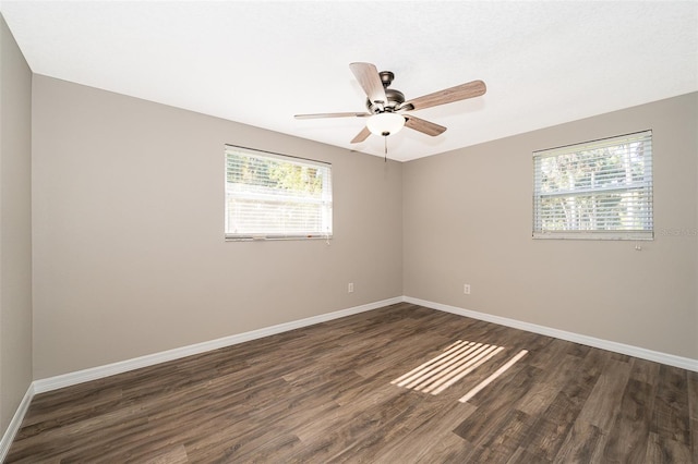 empty room with dark wood finished floors, baseboards, and ceiling fan