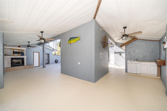 interior space featuring a tiled fireplace, lofted ceiling, concrete flooring, and ceiling fan