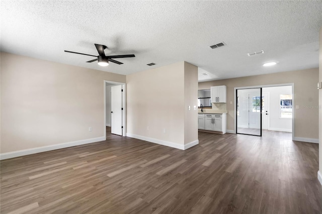 unfurnished living room with dark wood finished floors, baseboards, and visible vents