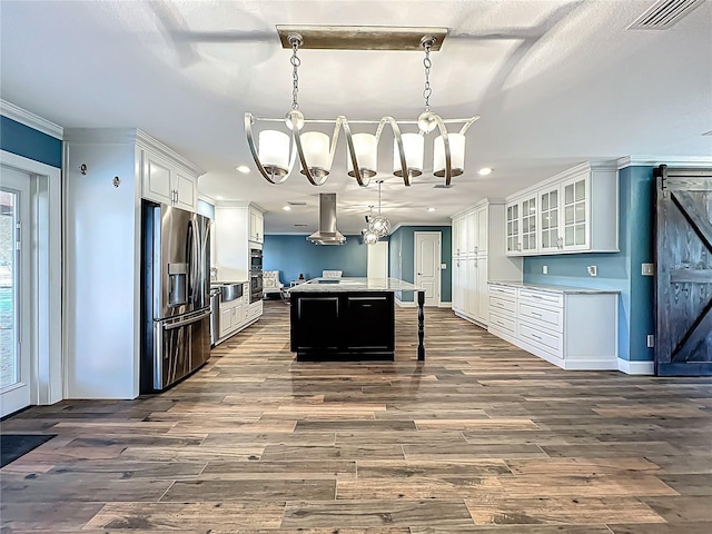 kitchen with visible vents, a kitchen island, stainless steel appliances, white cabinetry, and island range hood