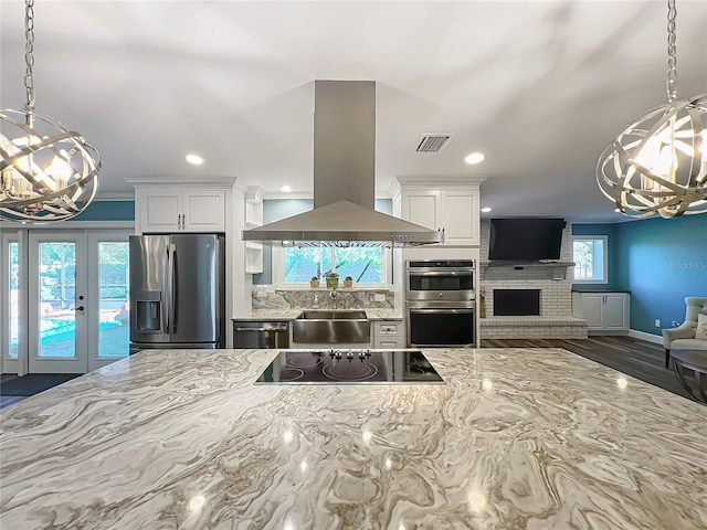 kitchen featuring visible vents, appliances with stainless steel finishes, island exhaust hood, and an inviting chandelier