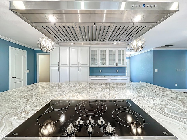 kitchen with glass insert cabinets, black electric stovetop, light stone countertops, custom range hood, and ornamental molding