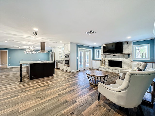 living room featuring visible vents, baseboards, a fireplace, french doors, and wood finished floors