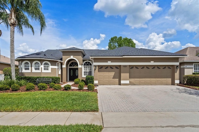 mediterranean / spanish house featuring an attached garage, driveway, stucco siding, and a front lawn