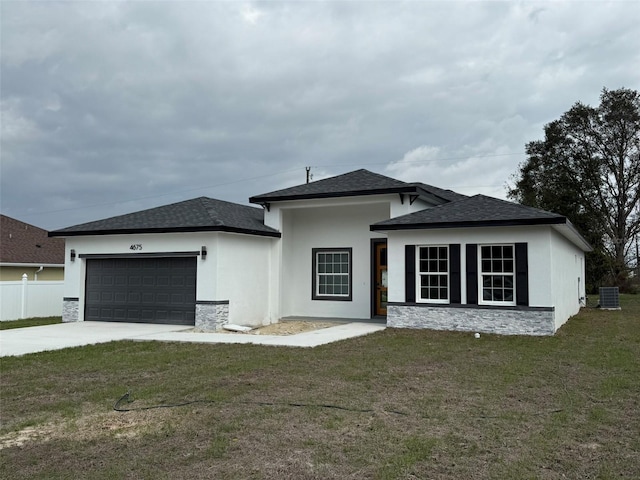 view of front of property with a shingled roof, central air condition unit, a front yard, a garage, and driveway