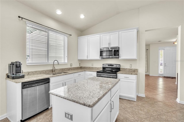 kitchen with a center island, vaulted ceiling, stainless steel appliances, white cabinetry, and a sink