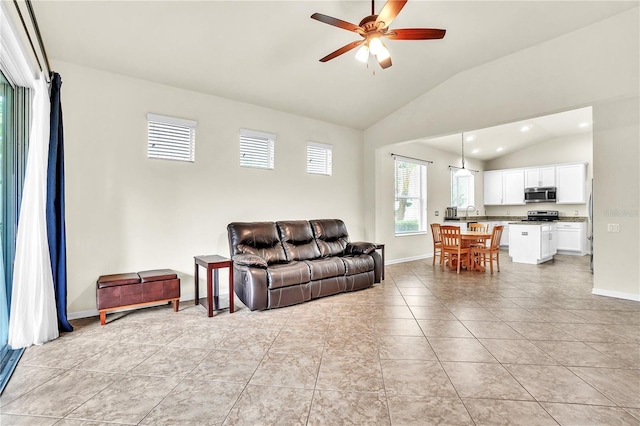 living area featuring baseboards, lofted ceiling, ceiling fan, and light tile patterned flooring