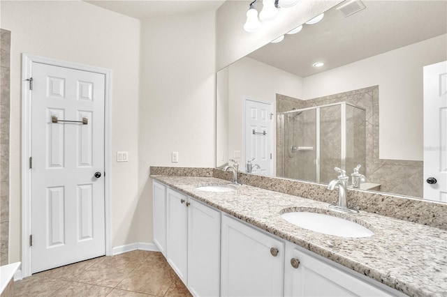 bathroom with double vanity, tile patterned floors, a stall shower, and a sink