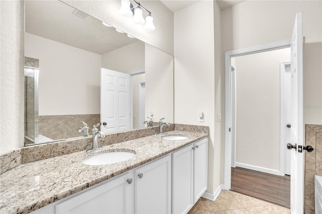 bathroom featuring double vanity, a tub to relax in, tile patterned floors, and a sink