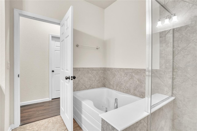 full bath with baseboards, a garden tub, and tile patterned flooring