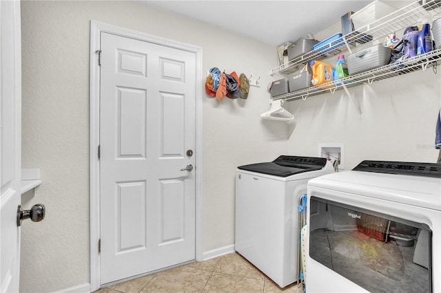 washroom featuring baseboards, light tile patterned flooring, laundry area, and washer and clothes dryer