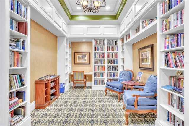 living area with built in shelves, a chandelier, ornamental molding, wall of books, and recessed lighting