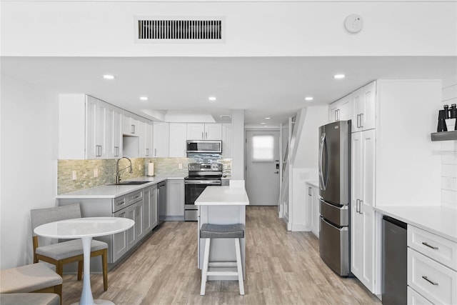 kitchen with visible vents, a sink, stainless steel appliances, light wood-style floors, and light countertops