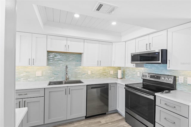 kitchen featuring visible vents, gray cabinetry, a sink, light countertops, and appliances with stainless steel finishes