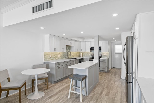 kitchen with a sink, visible vents, backsplash, and gray cabinets