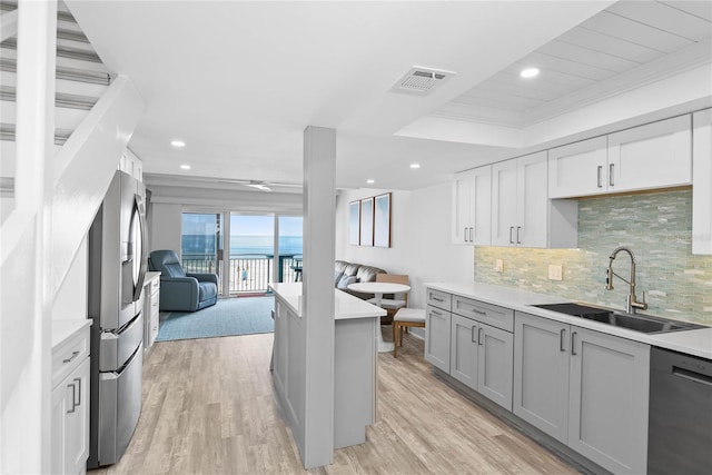 kitchen with visible vents, a sink, open floor plan, stainless steel fridge, and dishwasher