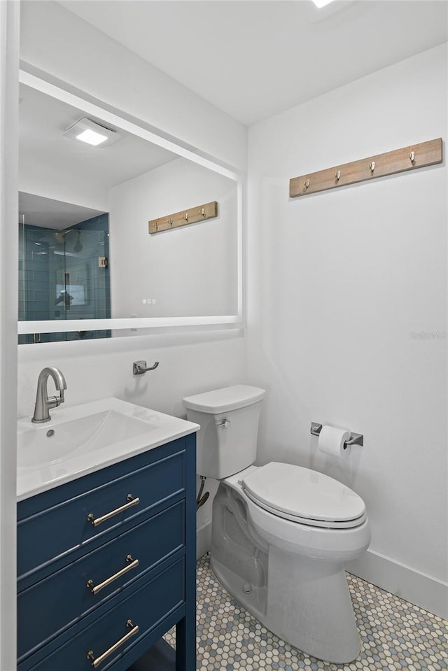 bathroom with vanity, toilet, baseboards, and a shower with shower door