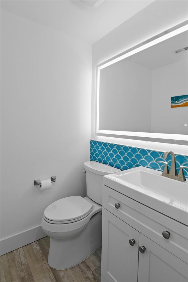 bathroom with visible vents, toilet, vanity, and wood finished floors