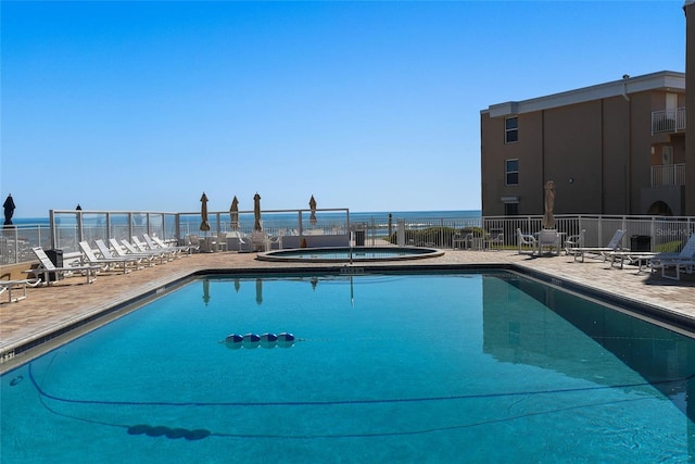 view of pool featuring a patio, a community hot tub, a water view, and fence