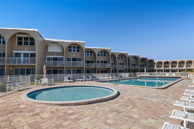 community pool with a patio and fence