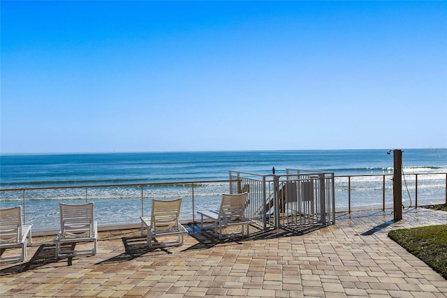 view of patio / terrace with a water view and a beach view