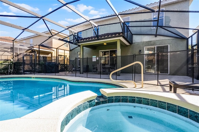 view of pool with a lanai, a pool with connected hot tub, and a patio