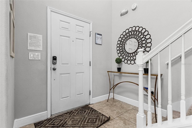 entryway with stairs, tile patterned floors, and baseboards