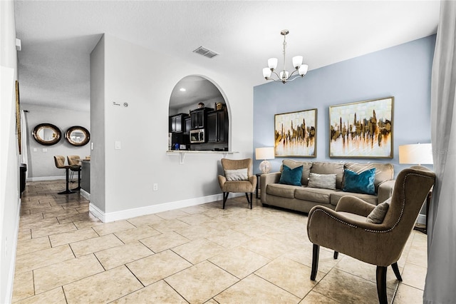 living room featuring light tile patterned floors, visible vents, baseboards, and an inviting chandelier