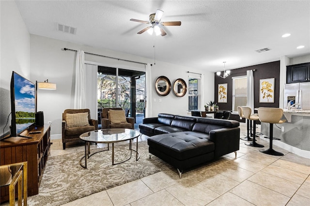 living area featuring light tile patterned floors, visible vents, and a textured ceiling