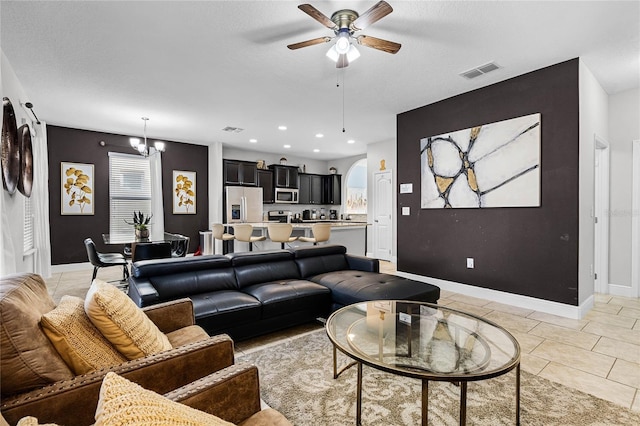 living area featuring visible vents, baseboards, ceiling fan with notable chandelier, recessed lighting, and arched walkways