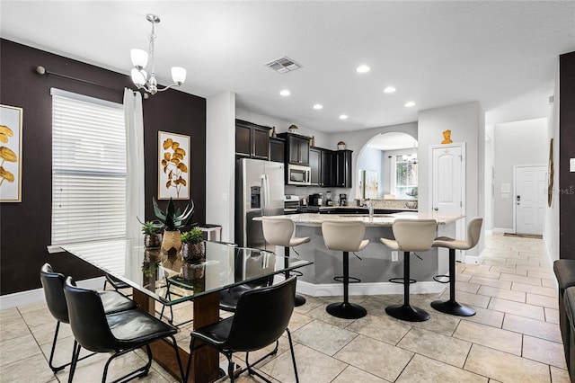 dining area featuring light tile patterned floors, arched walkways, visible vents, and a chandelier