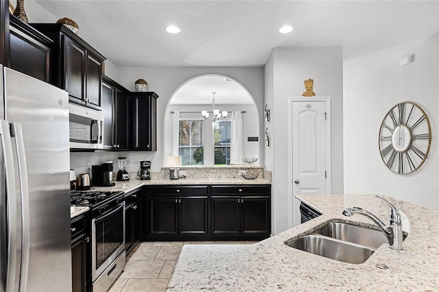 kitchen featuring a sink, light stone counters, recessed lighting, appliances with stainless steel finishes, and dark cabinets