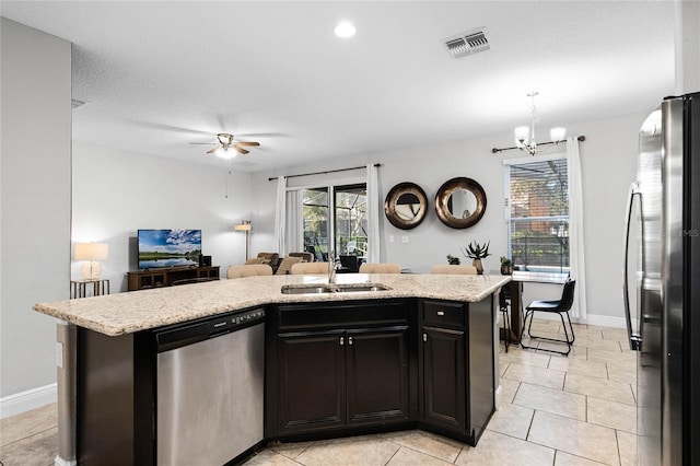 kitchen with visible vents, a kitchen island with sink, a sink, open floor plan, and appliances with stainless steel finishes