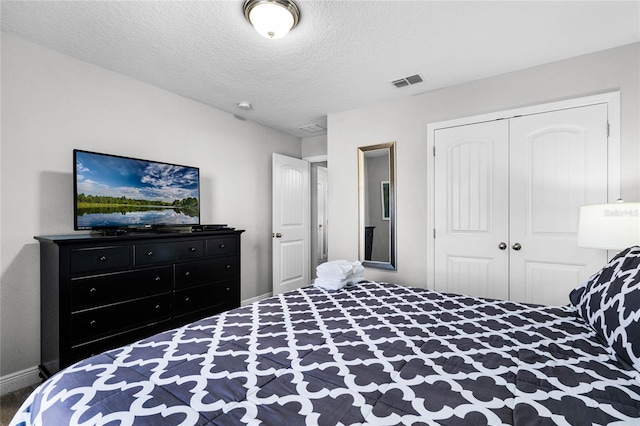 bedroom featuring baseboards, visible vents, a closet, and a textured ceiling