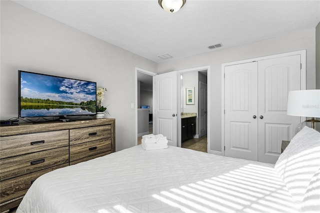 bedroom with a closet, visible vents, and ensuite bath