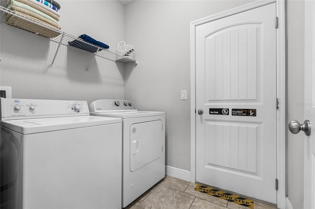 washroom featuring light tile patterned floors, laundry area, washer and dryer, and baseboards