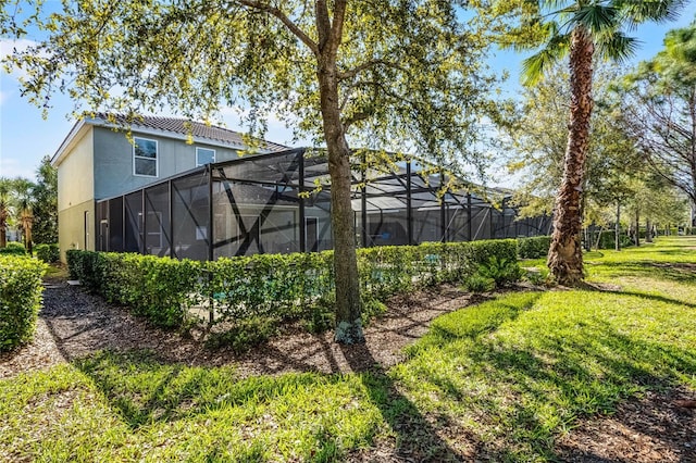 rear view of house with a lanai, a yard, and stucco siding