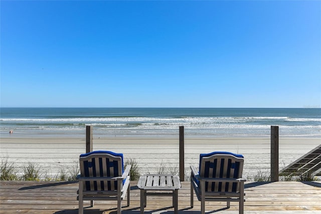 wooden terrace featuring a water view and a view of the beach