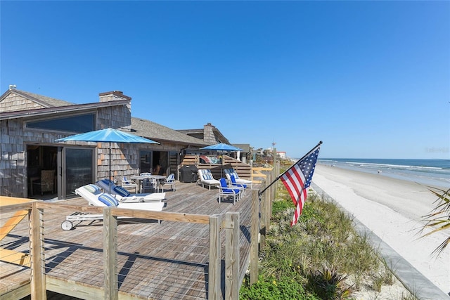 wooden terrace featuring a water view and a view of the beach