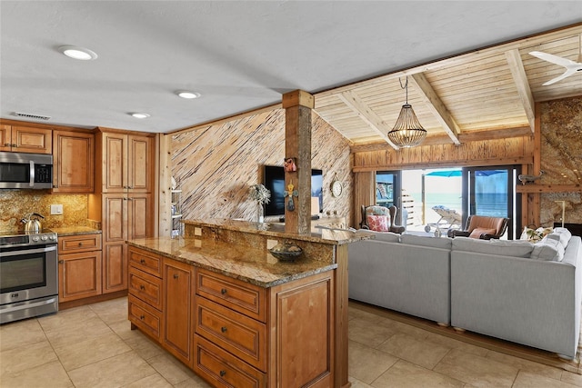 kitchen featuring light stone countertops, stainless steel appliances, decorative backsplash, open floor plan, and brown cabinets