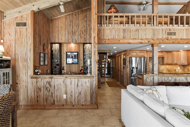 living area with visible vents, beam ceiling, wooden walls, and wood ceiling