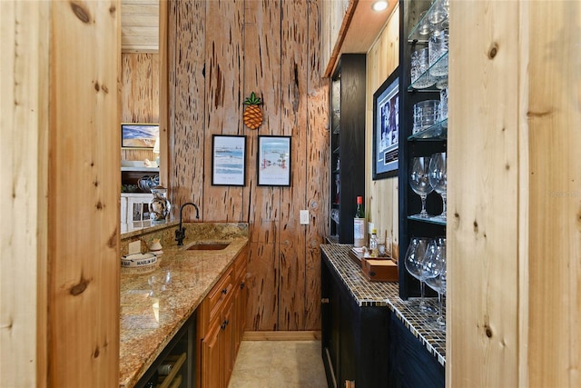 bar featuring a sink, indoor wet bar, wine cooler, and wooden walls