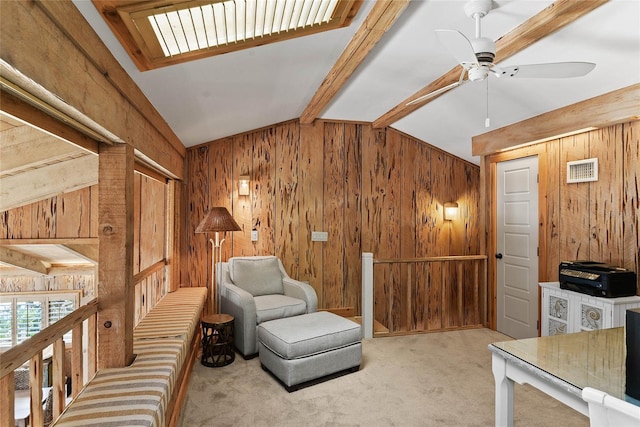 living area featuring vaulted ceiling with beams, carpet, wood walls, and ceiling fan