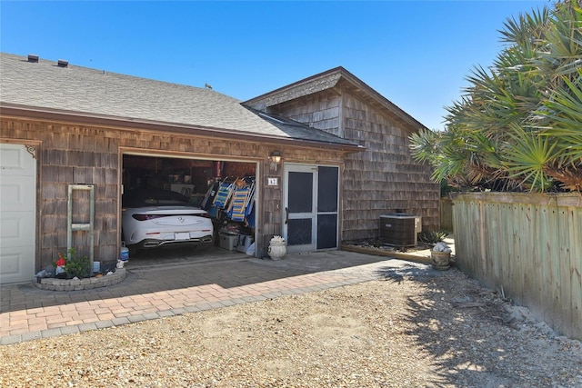 garage featuring driveway, central AC, and fence