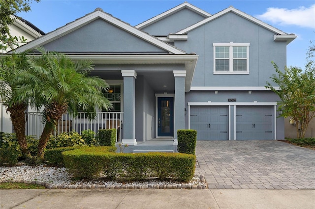 view of front of house with fence, covered porch, stucco siding, a garage, and decorative driveway