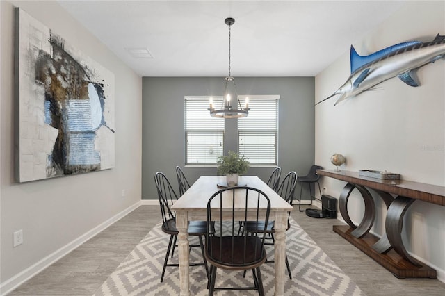 dining space featuring a notable chandelier, light wood-type flooring, and baseboards